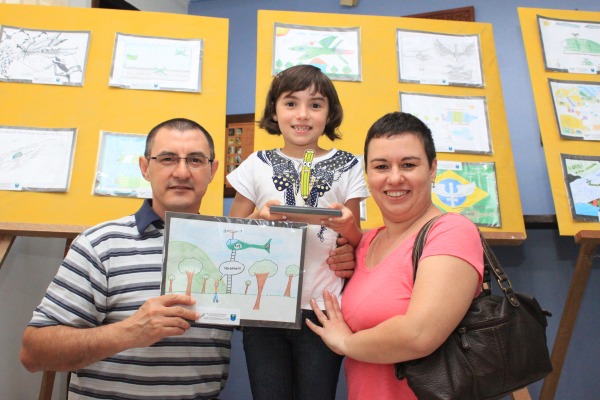 Aluna Manuela com seu troféu, desenho e seus pais   Sd Tiago Lopes