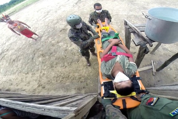 Equipe médica e homens de resgate levam o paciente de sua aldeia