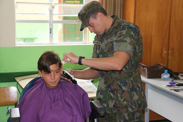 Militar da BAFL cortando cabelo de criança da comunidade